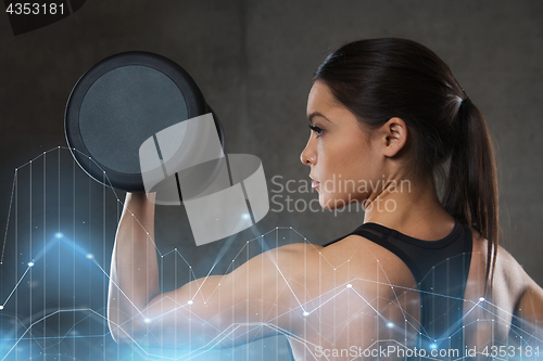 Image of young woman flexing muscles with dumbbells in gym