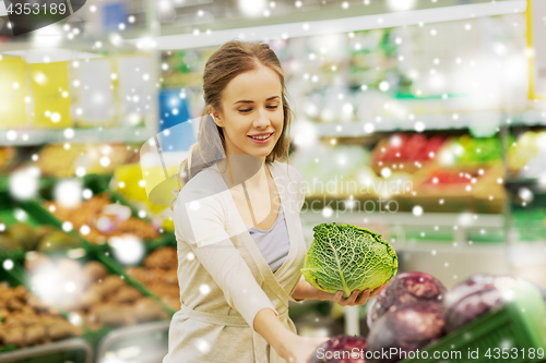 Image of happy woman buying savoy at grocery store