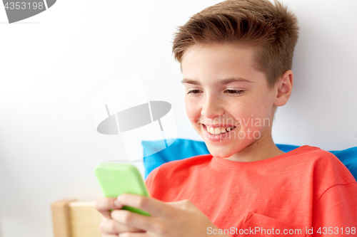 Image of happy smiling boy with smartphone at home