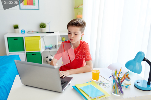 Image of student boy typing on laptop computer at home