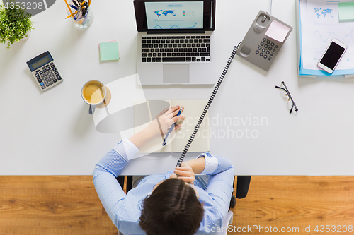 Image of businesswoman calling on phone at office table