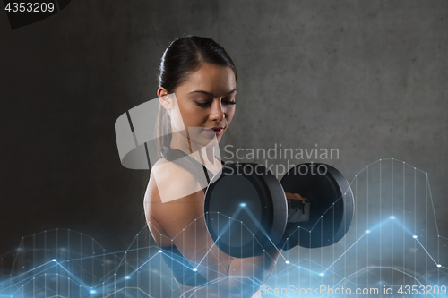 Image of young woman flexing muscles with dumbbells in gym