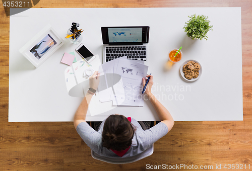 Image of woman with laptop and papers at office table