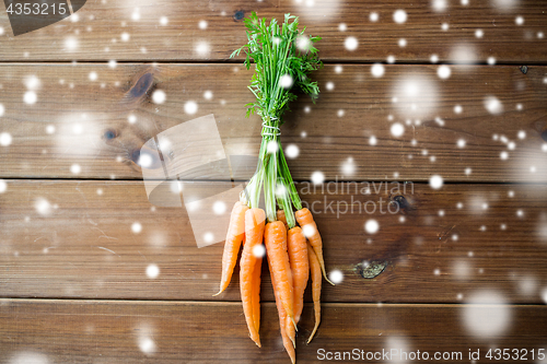 Image of close up of carrot bunch on wooden table