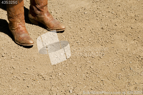 Image of Two dirty western cowboy boots standing on dirt ground