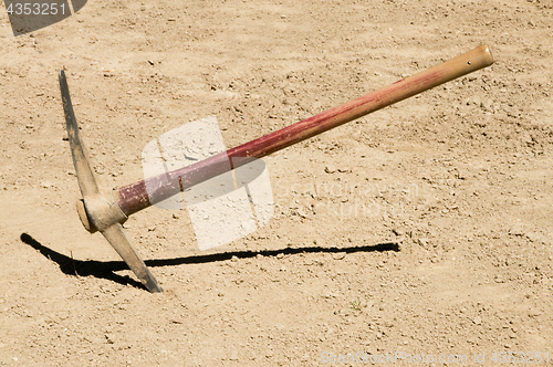 Image of Pick Ax plunged into dirt ground