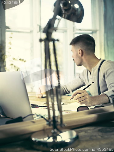 Image of Architect working on drawing table in office