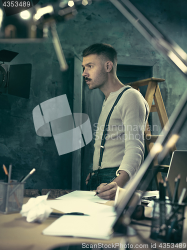 Image of Portrait of a bearded businessman who is checking details of his upcoming meeting in his notebook and typing.