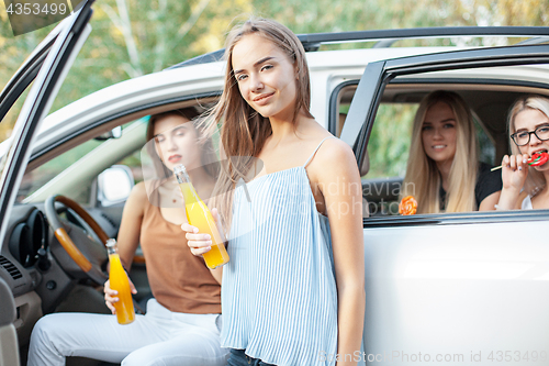 Image of The young women in the car smiling and drinking juice