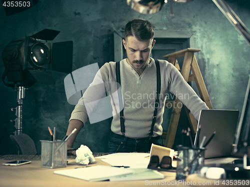 Image of Portrait of a bearded businessman who is checking details of his upcoming meeting in his notebook and typing.