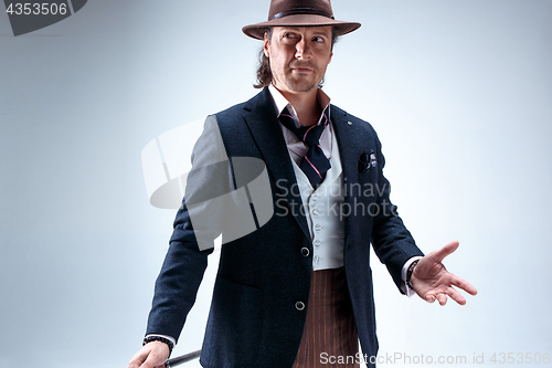 Image of The mature man in a suit and hat holding cane.