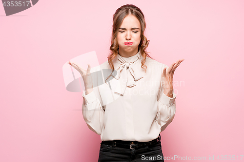 Image of The serious frustrated young beautiful business woman on pink background