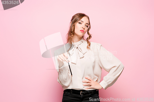 Image of The serious frustrated young beautiful business woman on pink background