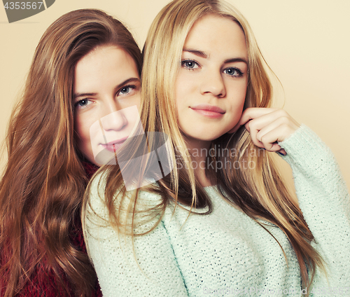 Image of Two young girlfriends in winter sweaters indoors having fun. Lif