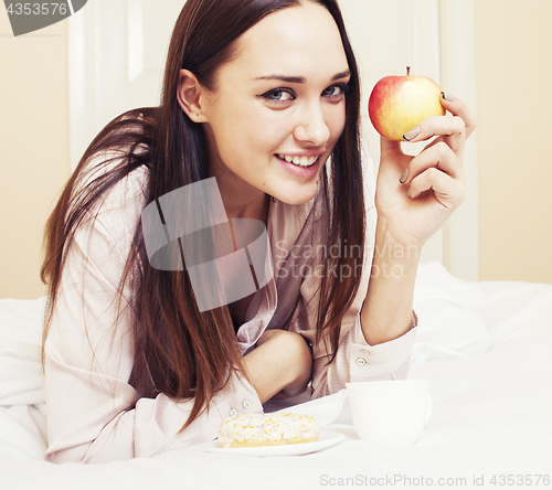 Image of young pretty brunette woman laying in bed, luxury white interior