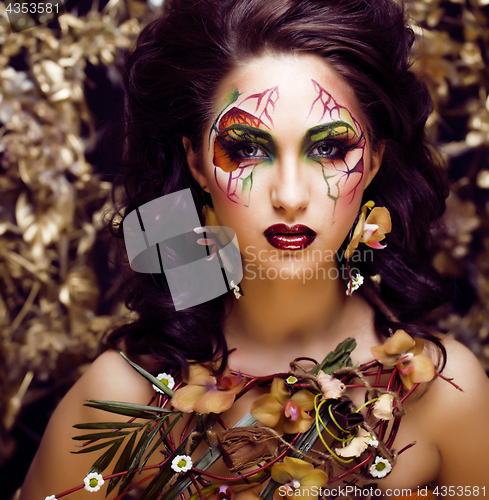 Image of beauty woman with face art and jewelry from flowers orchids clos