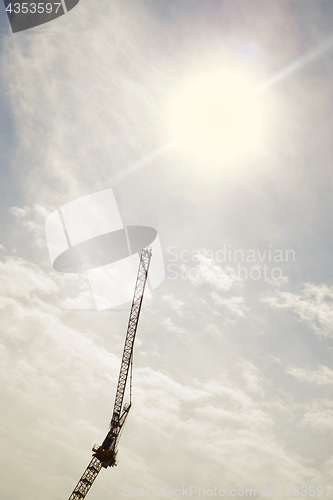 Image of Silhouette of construction crane against the sunny sky