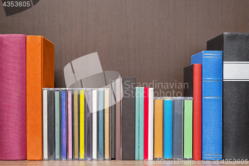 Image of stack of colorful books, cd and cassettes in the bookself