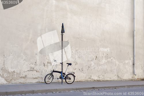 Image of Bicycle locked to the sign pole near the concrete wall