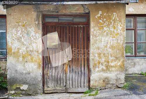 Image of wooden plank door with post box, dirty stucco wall background