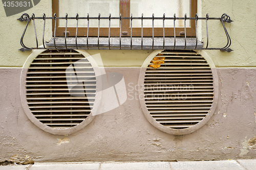 Image of abandoned grunge cracked stucco wall with ventilation grille holes