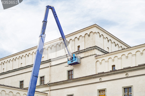 Image of construction worker fixing house facade using lifting boom machinery