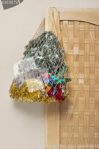 Image of Mesh bag full of tinsel, lights hanging on the wooden door