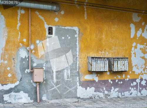 Image of Rusty mailboxes on cracked stucco wall