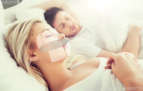 Image of happy couple sleeping in bed at home