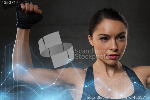 Image of young woman flexing muscles in gym