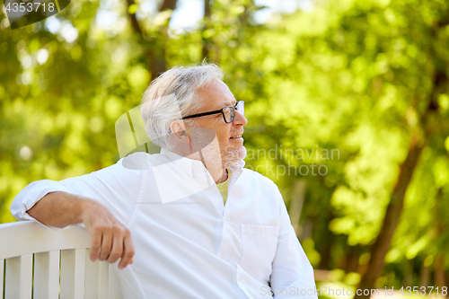 Image of happy senior man in glasses sitting at summer park