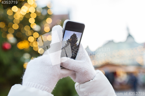 Image of hands with smartphone photographing christmas tree