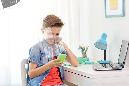 Image of happy boy with smartphone and laptop at home