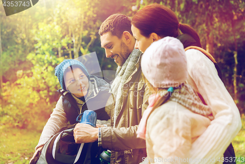 Image of happy family with backpacks and thermos at camp