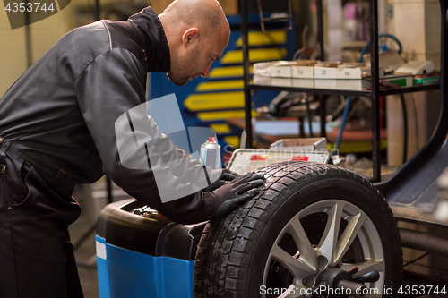 Image of auto mechanic balancing car wheel at workshop