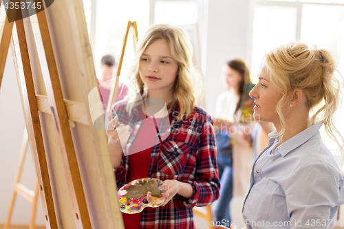 Image of artists discussing painting on easel at art school