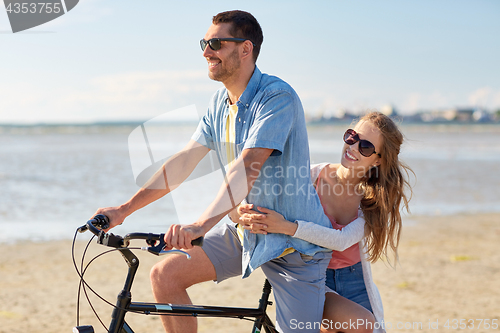 Image of happy young couple riding bicycle on beach 