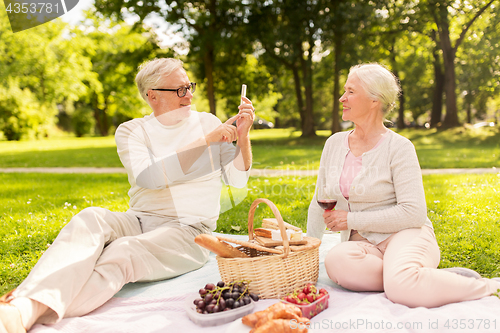 Image of senior couple taking picture by smartphone at park