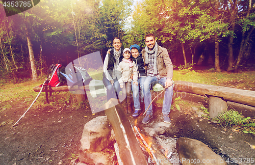 Image of happy family sitting on bench at camp fire