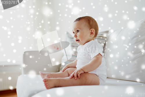 Image of happy baby boy or girl sitting on sofa at home