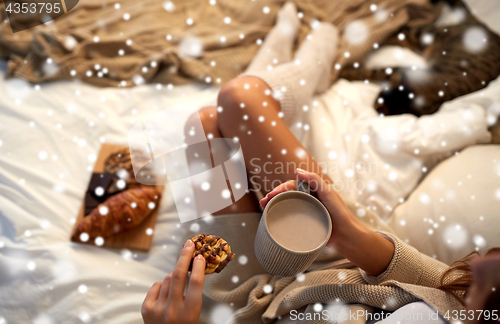 Image of close up of woman with cocoa cup and cookie in bed