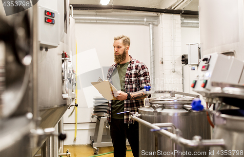 Image of man with clipboard at craft brewery or beer plant