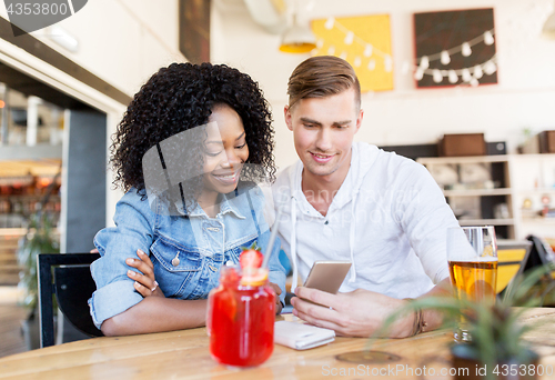 Image of happy man and woman with smartphone at bar