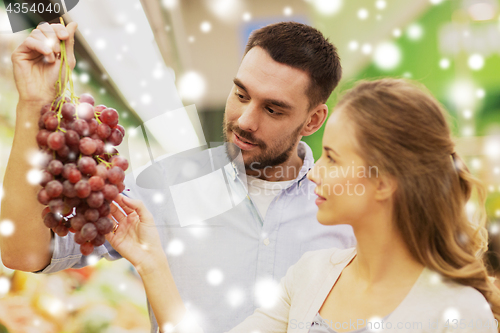 Image of happy couple buying grapes at grocery store