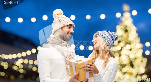 Image of happy couple with gift box over christmas lights