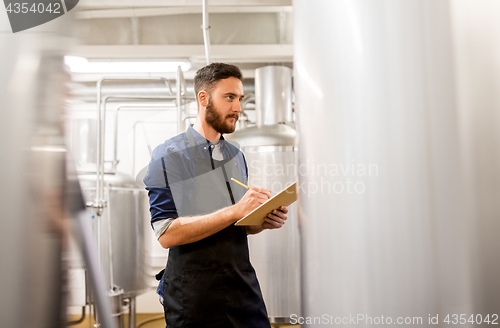 Image of man with clipboard at craft brewery or beer plant