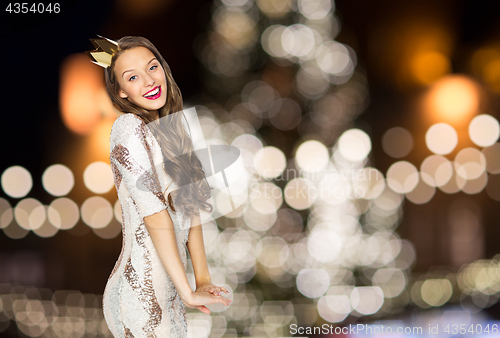 Image of happy woman in crown over christmas tree lights