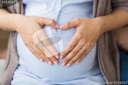 Image of close up of pregnant woman making heart on belly