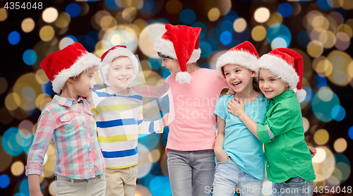 Image of happy little children in santa hats hugging