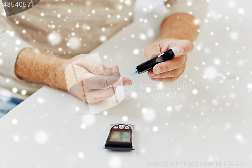 Image of senior man with glucometer checking blood sugar